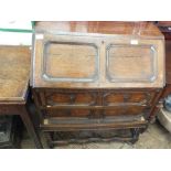 An oak bureau with panelled front doors and fitted interior on barley twist legs