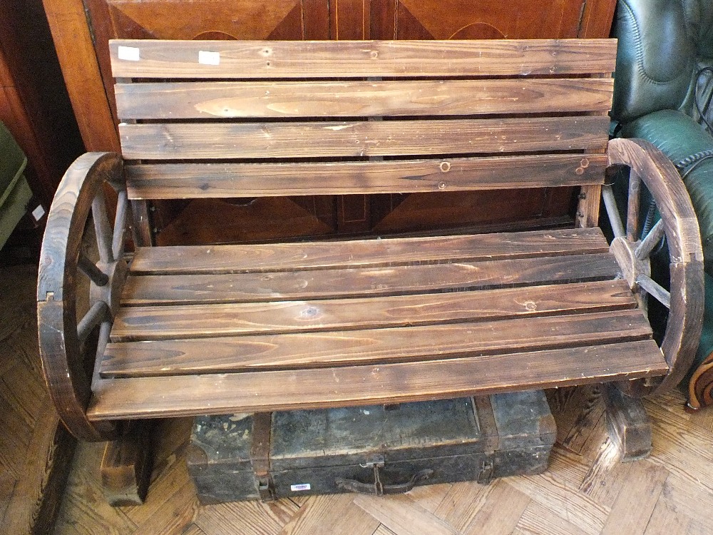 A wooden garden bench with cartwheel ends