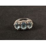 An 18ct white gold aquamarine three stone ring surrounded by diamonds