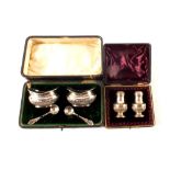 A cased set of salt and peppers plus cased silver mustards with matched spoons