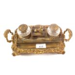 A Victorian brass two bottle inkstand with sphinx mount