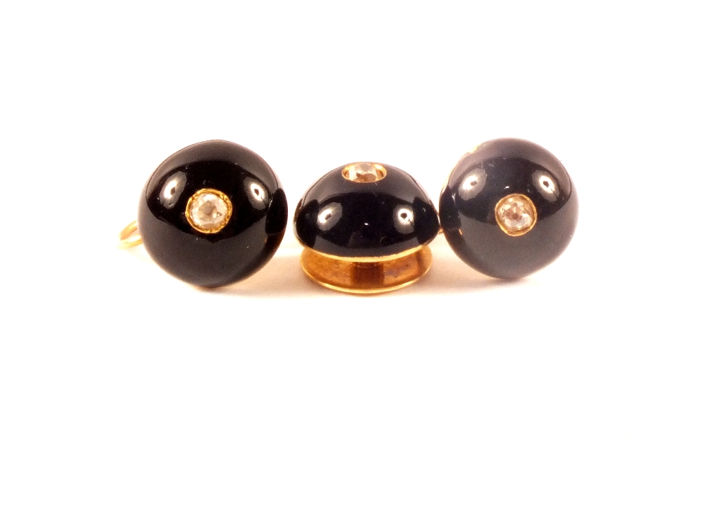 A pair of unmarked gold earrings with black enamel decoration set with single diamond centre plus a