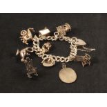 A silver charm bracelet with various charms including wishing well,