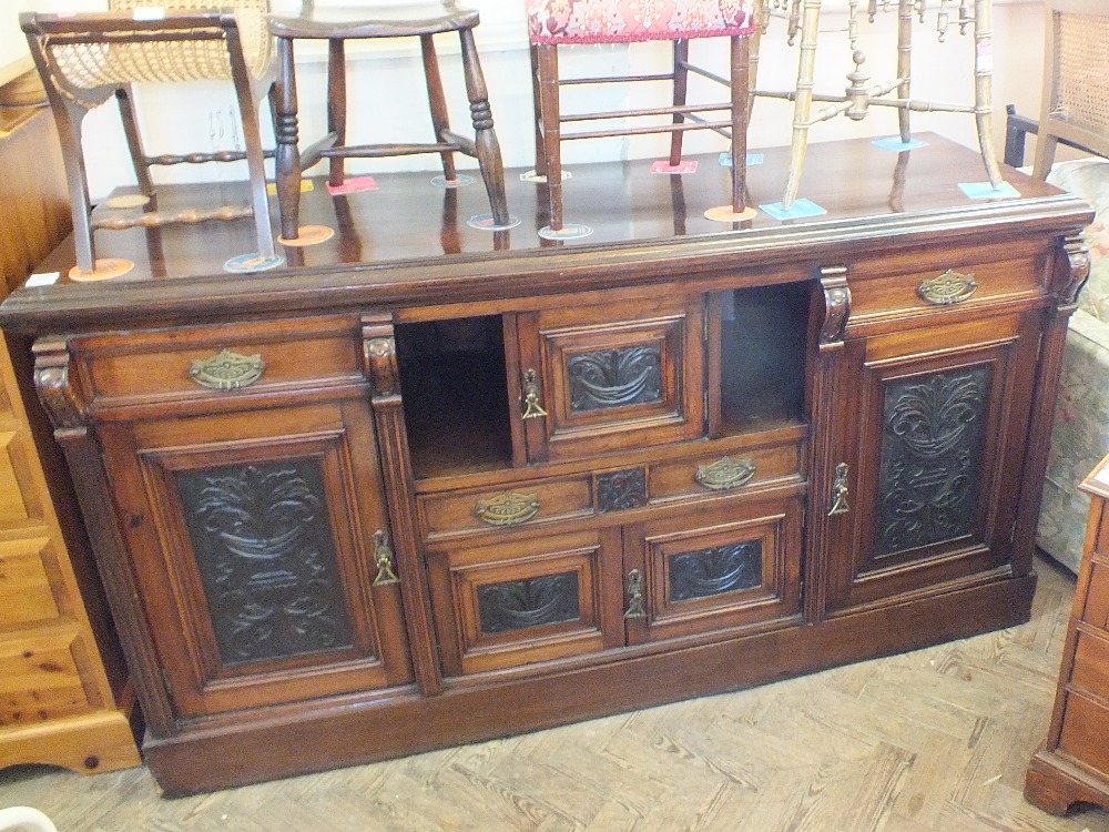 An Edwardian mahogany sideboard with carved panels and brass handles