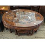 An Oriental style carved coffee table with six matching side tables/stools below