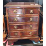 An oak apprentice chest of two short and three long drawers with brass ring handles and bracket