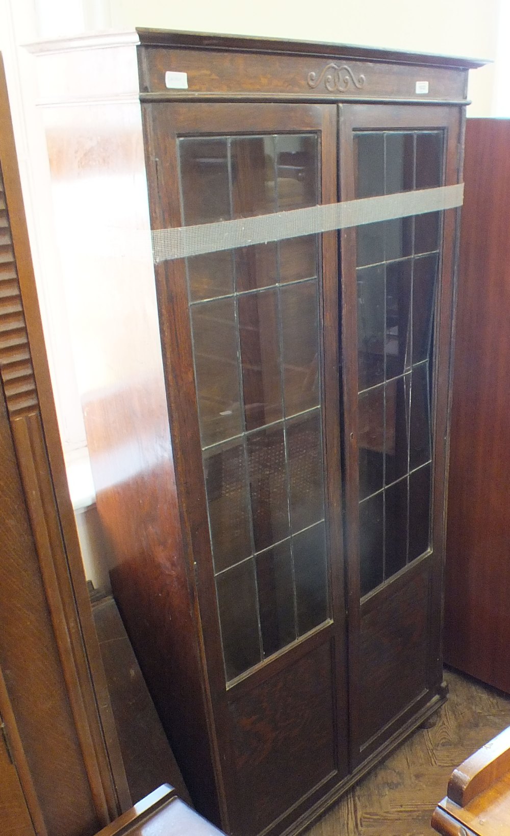 An oak glazed bookcase with lead lined glass doors