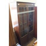 An oak glazed bookcase with lead lined glass doors