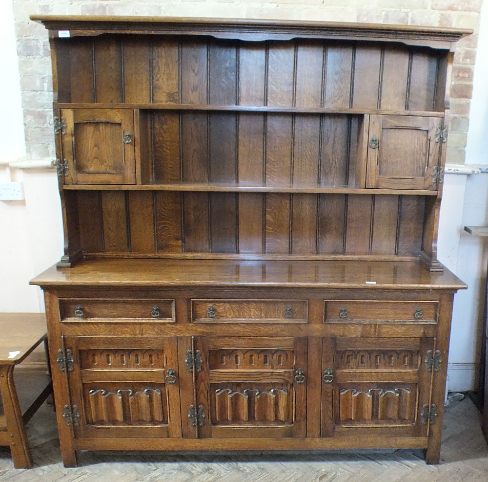 A vintage oak open back dresser with three drawers and three linen fold cupboard base