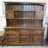 A vintage oak open back dresser with three drawers and three linen fold cupboard base