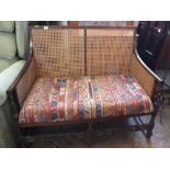 A Bergere two seater oak frame settee with barley twist arms
