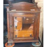 An oak smoker's cabinet with drop handles