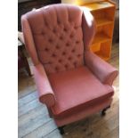 A pink button back wingback armchair