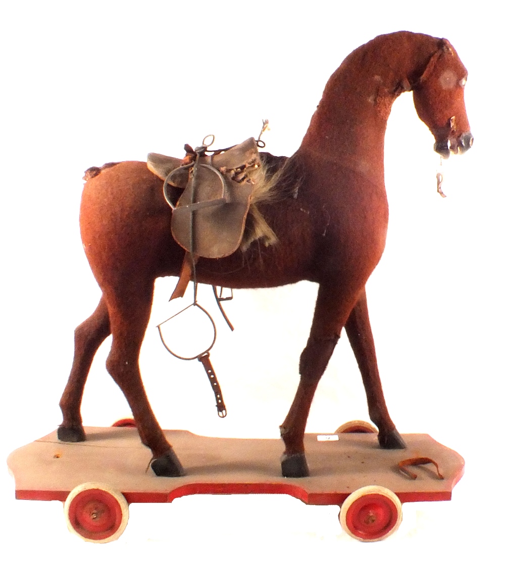 A wooden wheeled horse with felt hide and leather saddle,