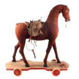A wooden wheeled horse with felt hide and leather saddle,