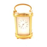 An oval brass carriage clock (chipped glass)