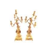 A pair of green onyx and gilt metal four branch candelabra supported by horn blowing cherubs (as