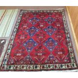A Persian red ground rug with six central medallions,