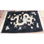 A Chinese black ground rug with dragon and flaming pearl decoration,