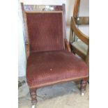 An Edwardian mahogany nursing chair with dark red upholstery on turned legs