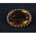 An oval citrine brooch mounted in yellow metal