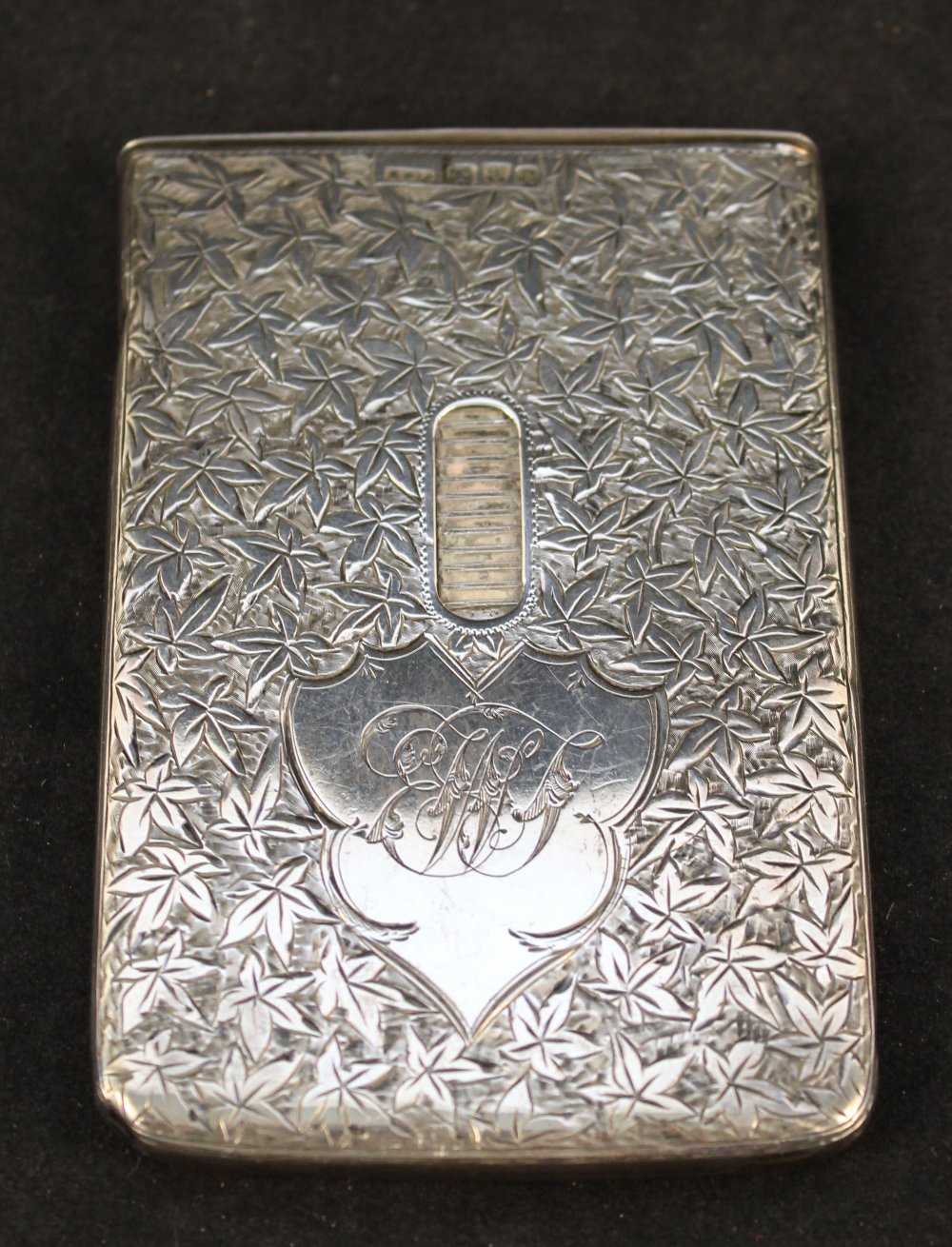 An unusual silver card case with engraved leaf decoration, sliding action to release cards,