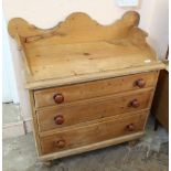 A Victorian stripped pine cottage chest of three drawers with carved upstand