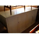 A white painted pine four door cupboard base