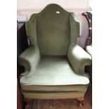 A green velour upholstered wingback armchair