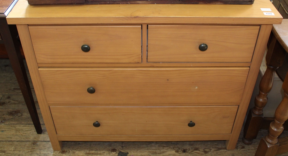 A modern faux pine chest of two short and two long drawers