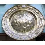 A 17th Century brass alms dish with repousse central decoration of a vase of flowers surrounded by