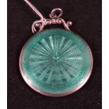 A silver circular mirror pendant with green enamel decoration