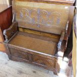 A carved oak monk's bench with folding top which converts to a table