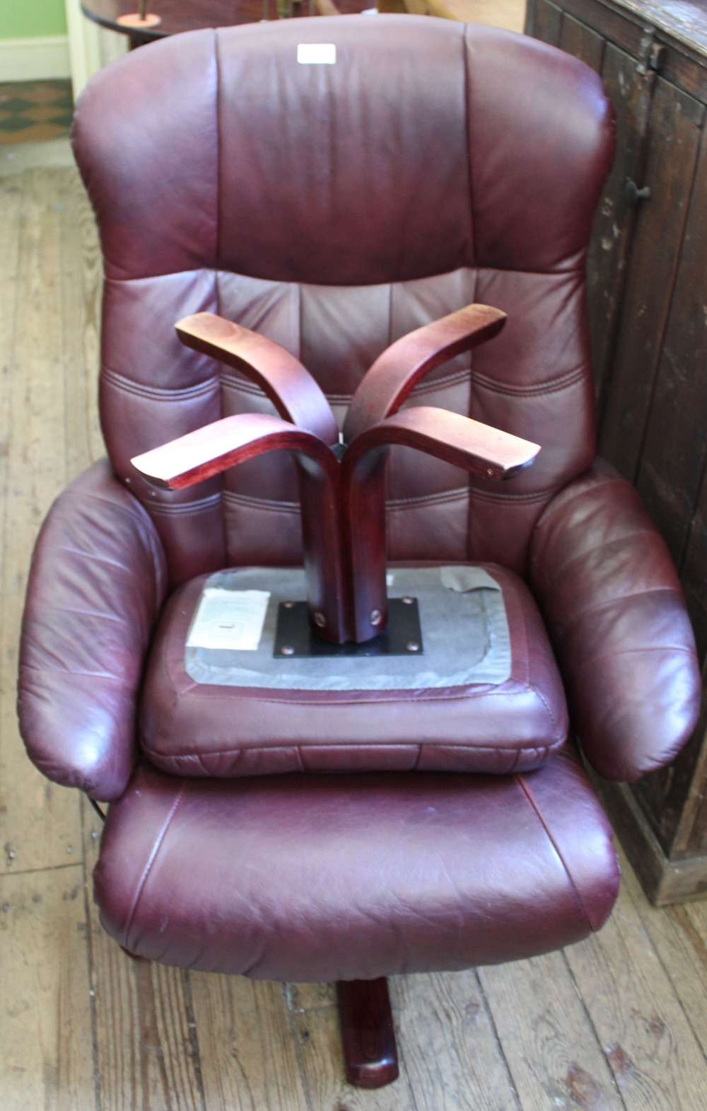 A maroon leatherette Stressless style swivel chair with matching footstool