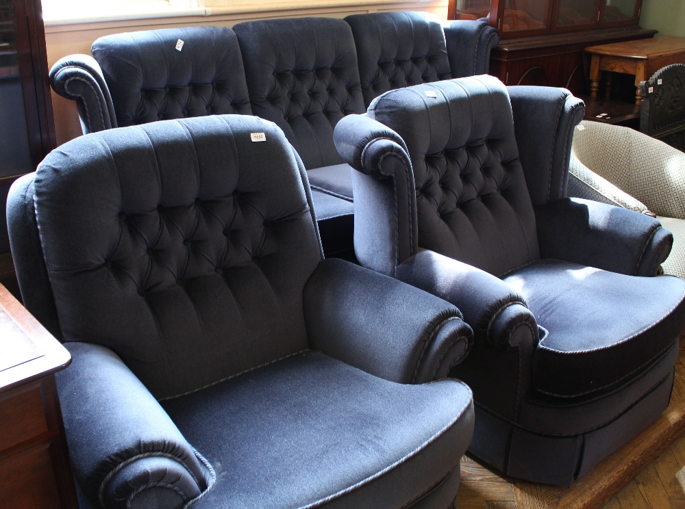 A blue velour button back three piece suite comprising a three seater sofa and two armchairs