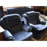 A blue velour button back three piece suite comprising a three seater sofa and two armchairs