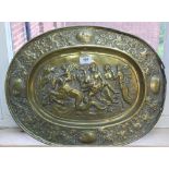 An oval brass wall plaque with battle scene depiction