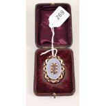 A yellow metal memorial brooch with garnet and pearl decoration and central hair panel under glass