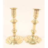 A pair of 18th Century seamed brass candlesticks with knopped stems and wide petal bases,