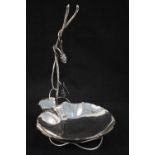 A silver wine bottle stand with applied grape and vine leaf decoration,