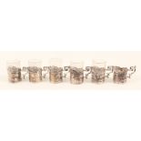 Six continental liquor glasses with silver holders decorated with embossed scenes,