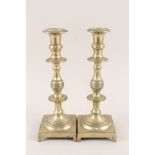 A pair of heavy 18th Century Spanish brass candlesticks having knopped stems and square bases with