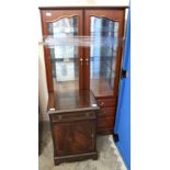 A three drawer display cabinet with two glazed doors and glass shelves and a reproduction pot