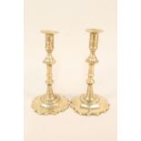 A pair of 18th Century brass candlesticks with knopped stems, ejectors and wide petal bases,