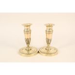 A pair of early 19th Century French brass and copper candlesticks with circles of fluted and chased