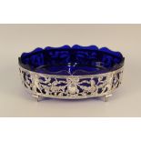 A large continental silver fruit bowl with pierced decoration on four feet with blue glass liner,