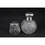 A silver top cut glass scent bottle with engraved monogram and a silver top cut glass jar with
