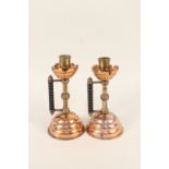 A pair of Arts and Crafts copper and brass candlesticks with bobbin turned ebonised side handles,