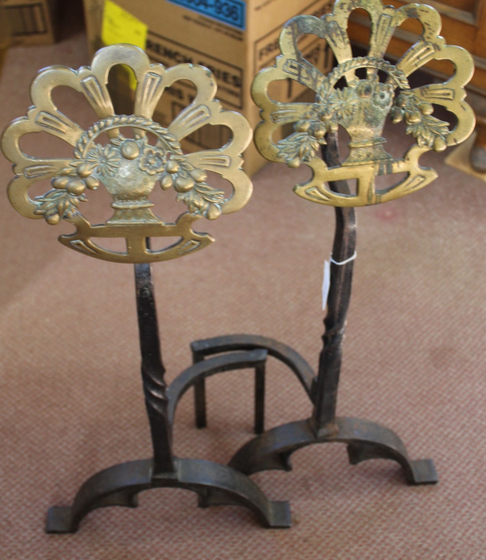 A heavy pair of Arts and Crafts wrought iron and pierced brass floral medallion fire dogs on arched