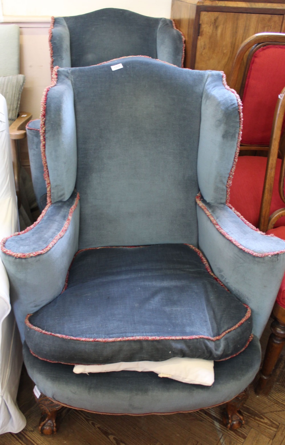A pair of wingback blue upholstered armchairs on mahogany ball and claw feet
